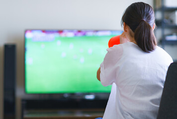 家でスポーツをテレビ観戦する若い女性のイメージ