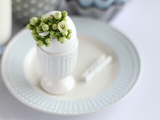 Breakfast. An eggshell vase with a bunch of white flowers stands on the table.