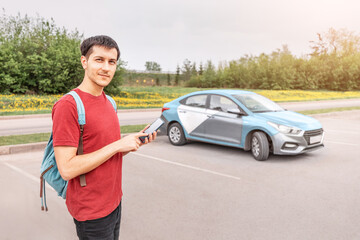 young person on a smartphone books a car or taxi in the carsharing app to get around the city. New...