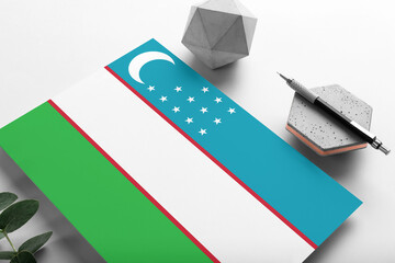 Uzbekistan flag on minimalist paper background. National invitation letter with stylish pen on stone. Communication concept.
