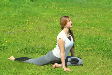 Young woman of European appearance does yoga in summer nature