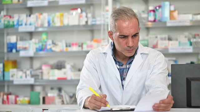 Portrait of caucasian pharmicist checking prescription working at drug store