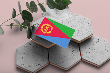 Eritrea flag on hexagon stylish stones. Pink copy space background. Flat lay, top view minimal national concept.