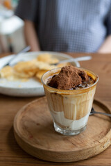 hot piccolo latte coffee with chocolate malt powder on top of glass is a special menu at coffee shop on wooden table.