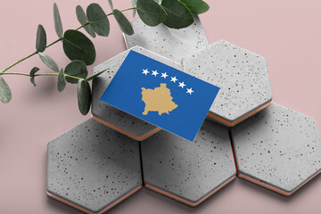 Kosovo flag on hexagon stylish stones. Pink copy space background. Flat lay, top view minimal national concept.