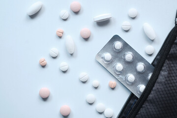 Top view of white pills spilling on white desk 