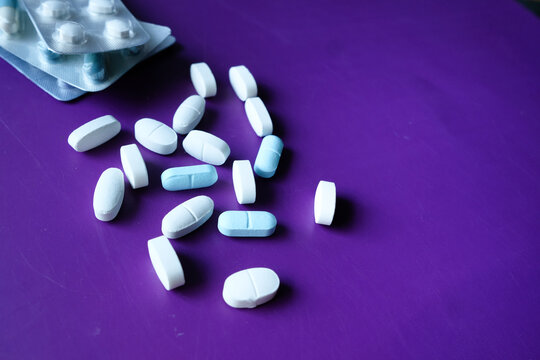 Close Up Of Pills Spilling On Purple Desk 