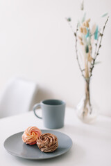 Cup of coffee with marshmallows and flowers on the table. Romantic morning. Tasty breakfast. Flat lay, top view, copy space.