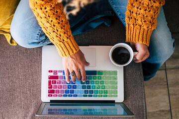 Vertical view adult woman hands  working and writing on a coloured laptop keyboard while drink a...