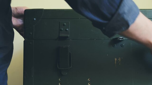 Man's Hands Open Green Military Storage Box for Ammunition. Green box from the War with Scratches and Locks in front.