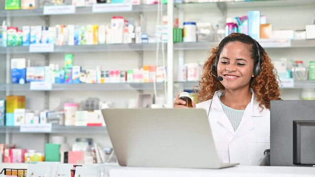 Happy young African American mixed race pharmacist listening to music and dancing in a drug store