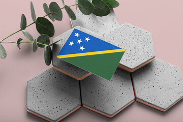 Solomon Islands flag on hexagon stylish stones. Pink copy space background. Flat lay, top view...