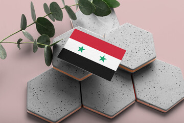 Syria flag on hexagon stylish stones. Pink copy space background. Flat lay, top view minimal national concept.