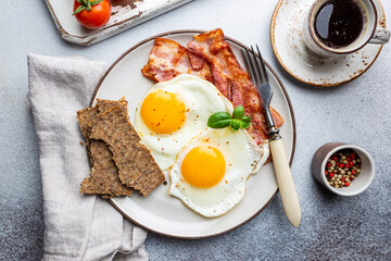 Fried eggs and bacon for breakfast on a plate, top view, copyspace