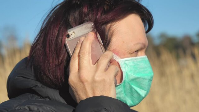 A closer look of the lady talking on the phone with her face mask
