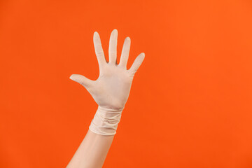 Profile side view closeup of human hand in white surgical gloves showing number five with hand or waving hand to greeting. indoor, studio shot, isolated on orange background.