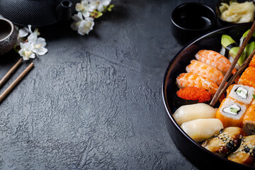 Set of sushi and maki with soy sauce over black background. Top view with copy space