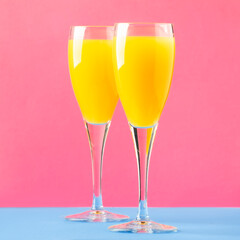 Mimosa alcohol cocktail with orange juice and dry champagne or sparkling wine in glasses, blue pink...