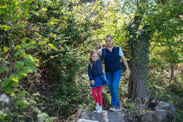 Naklejka na ściany i meble Father and daughter walking on a log in a park in summer. Copy space. Lifestyle concept.