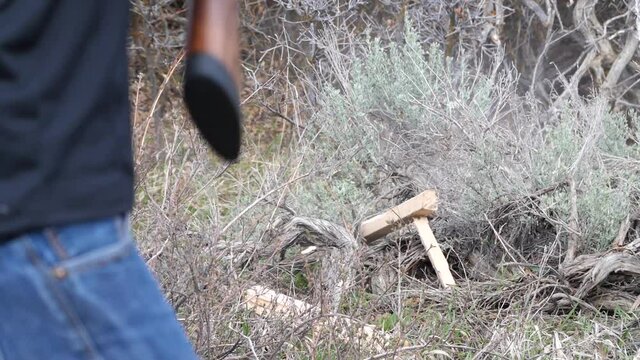 Man shoots piece of wood block with shotgun slow motion. 