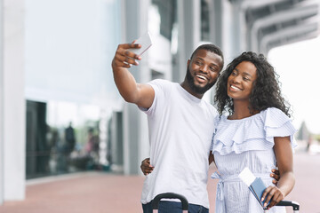 Honeymoon Memories. Happy romantic black couple taking selfie near airport terminal