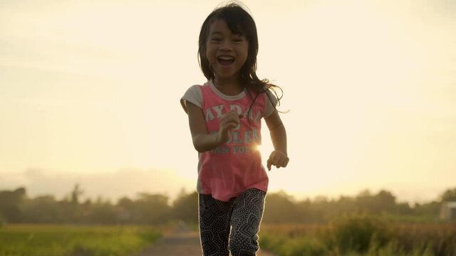happy girl running on empty road during sunset