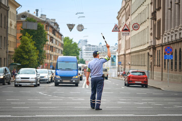 Policeman directing traffic in the city. Traffic police adjusts traffic at the intersection of ...