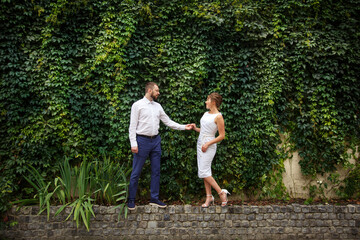 Young Bride and Groom couple in summer old City garden. Tender look on each other. Woman and man couple. Romantic walk of young happy family near hydrangea bush. lovers newlyweds street style wedding