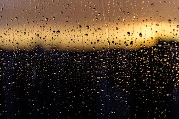 Rain drops on a window during a storm in sunset time