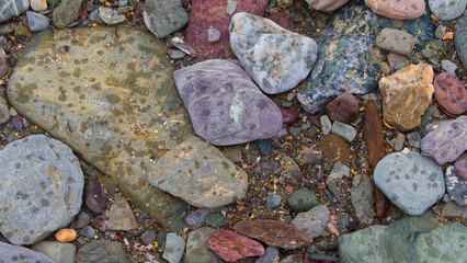 Textural backgrounds of beach pebbles, rocks and sand along the strand line of a sheltered Cornish beach.