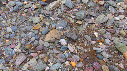 Textural backgrounds of beach pebbles, rocks and sand along the strand line of a sheltered Cornish beach.