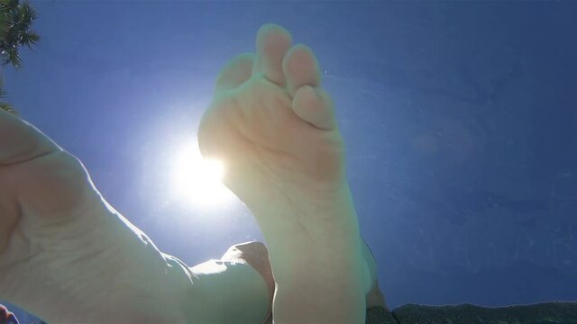 Extreme close-up from underwater of dangling feet moving around in the water