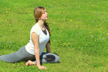 Young woman of European appearance does yoga in summer nature