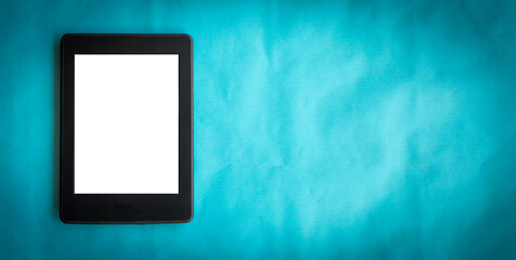 A modern black electronic book with a white blank empty screen on vintage blue background and empty space - 357463221