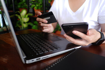 Cropped shot view of woman or man hands holding credit card, typing on laptop computer keyboard for...