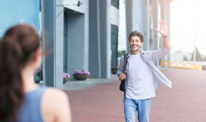 Long-awaited meeting. Man waving hand, greeting girlfriend after arriving to airport