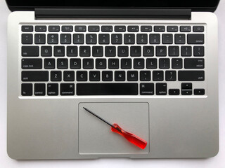 Top view of modern laptop computer with screwdriver on touchpad. Laptop repair concept, teardown.