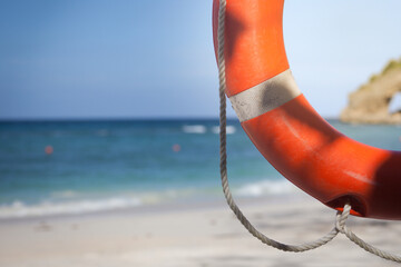 Part of red life ring with rope hanging near the beach