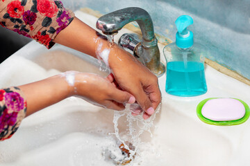 Women use liquid soap for rubbing and washing her hands under the water tap. Hygiene concept. Wash hands to stop spreading coronavirus.