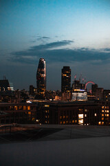 London cityscape at night with florescent lights in the buildings against a blue sky