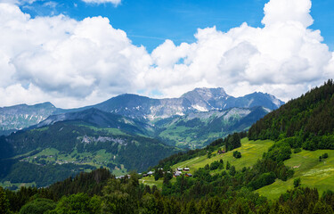 Fototapeta na wymiar Amazing summer panorama with mountains, small village, green meadows and cloudly blue sky in Swiss Alps. Oberland, Switzerland.