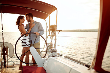 Man and woman sailing on a boat at vacation at romantic sunset.
