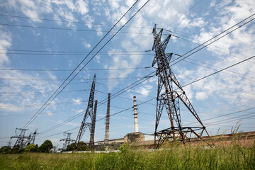Line of high voltage equipment in sunny summer day in meadow. Blue sky. Grees grass