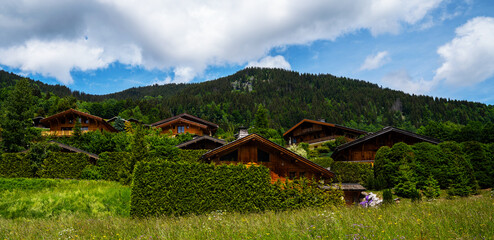 Wooden houses in Alps, Italy. Country cottages with log and timber in the green mountaun area. Cozy eco-friendly houses made of natural wood, bungalows for families.
