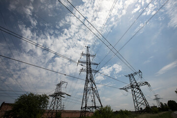 Line of high voltage equipment in sunny summer day in meadow. Blue sky. Grees grass