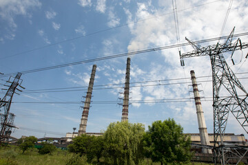 Line of high voltage equipment in sunny summer day in meadow. Blue sky. Grees grass