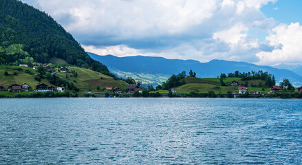 Panoramic view of idyllic scenery Lake Lungern with fresh green meadows. Beautiful sunny day in springtime in Switzerland. Summer rural view. Village in green mountain valley.