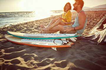 Obraz premium Young man and woman camping on the beach during the sunset.
