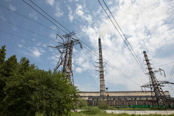 Line of high voltage equipment in sunny summer day in meadow. Blue sky. Grees grass