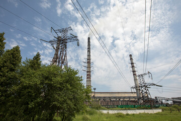 Line of high voltage equipment in sunny summer day in meadow. Blue sky. Grees grass